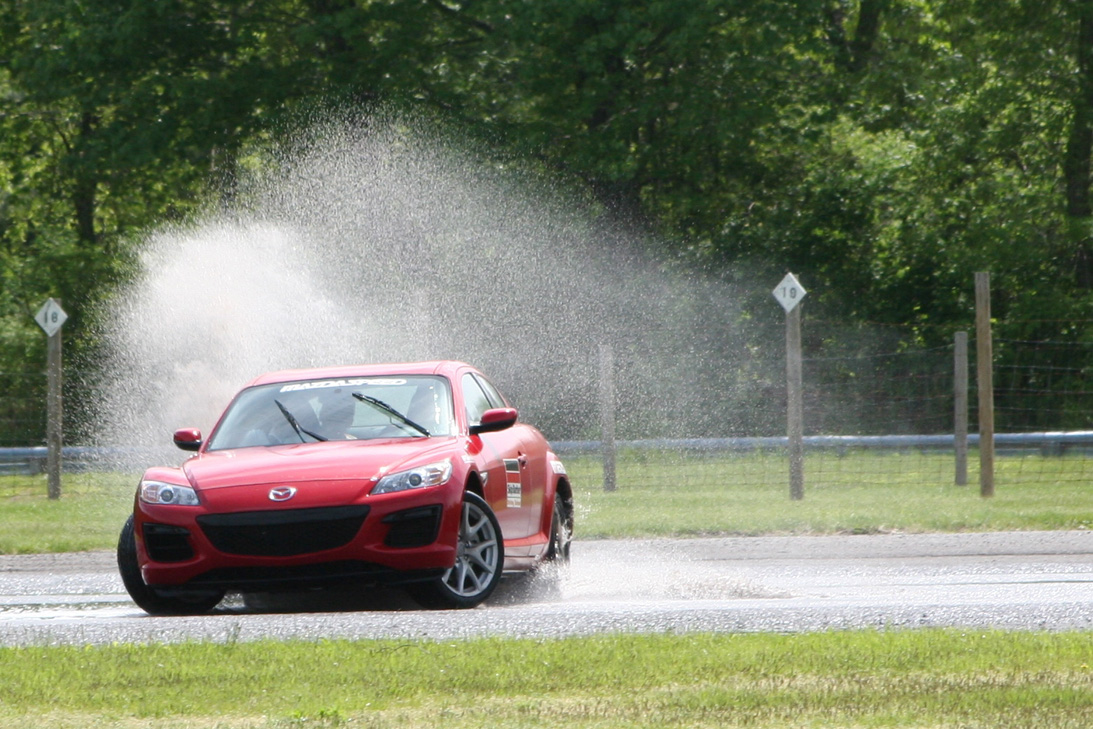 A red car practising vehicle control on a wet skidpad